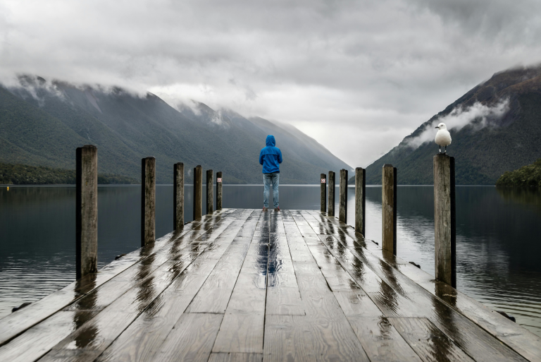 Self-Creation: How To Become Who You Are: a man standing on a dock facing the lake and the mountain