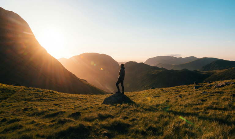 silence the doubters with action: a man standing on top of the rock in the mountain watching the sunset
