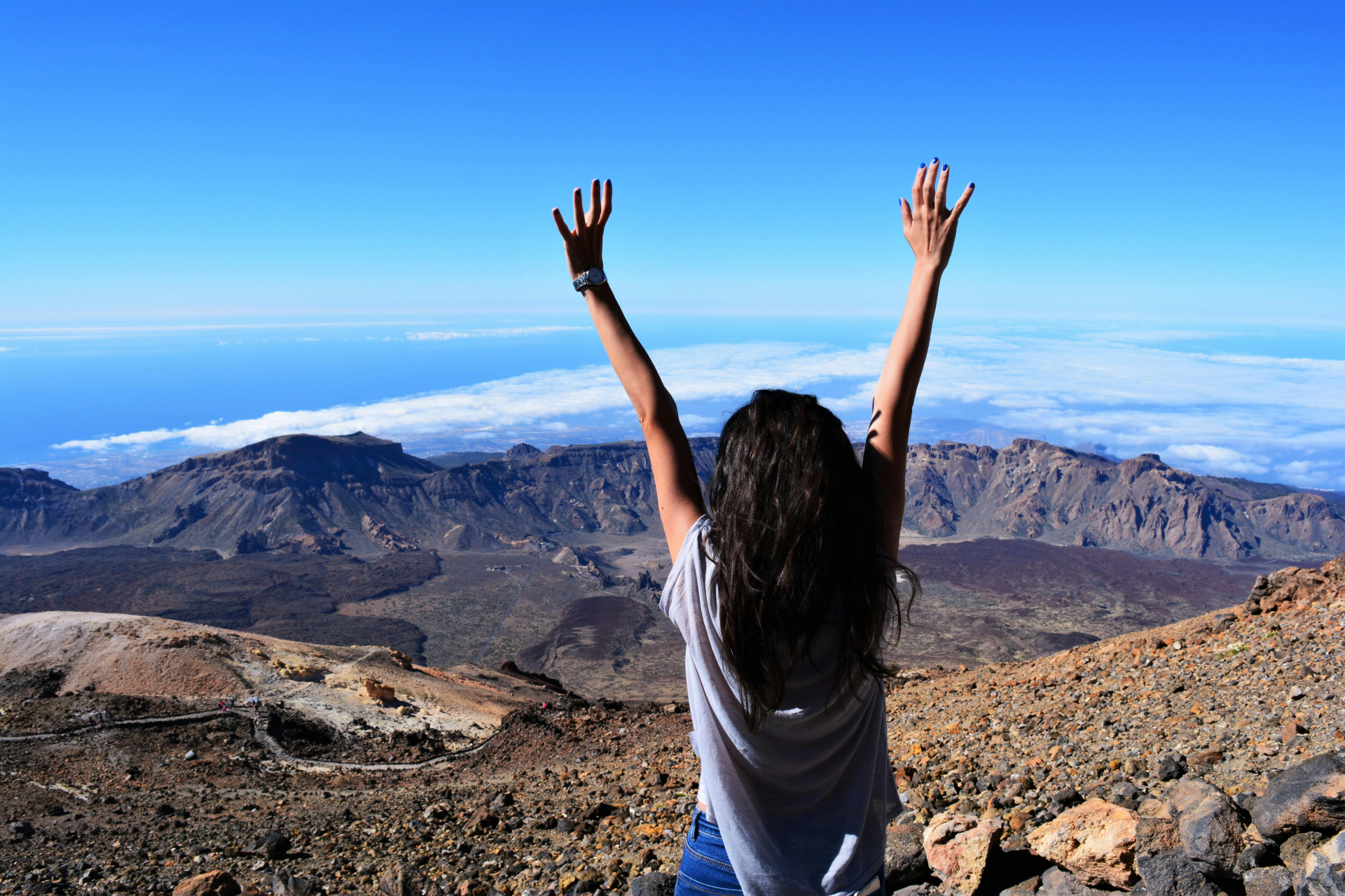 Let Go Of the Past: a woman on top of a rocky mountain raising her both hands