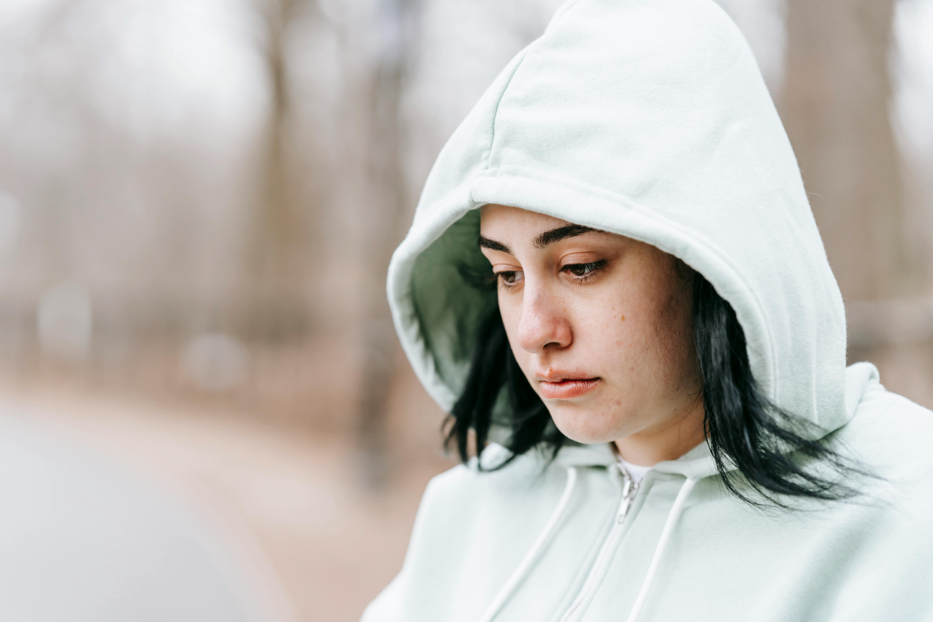 Overcoming Learned Helplessness: a woman wearing a white jacket with hoodie looking sad