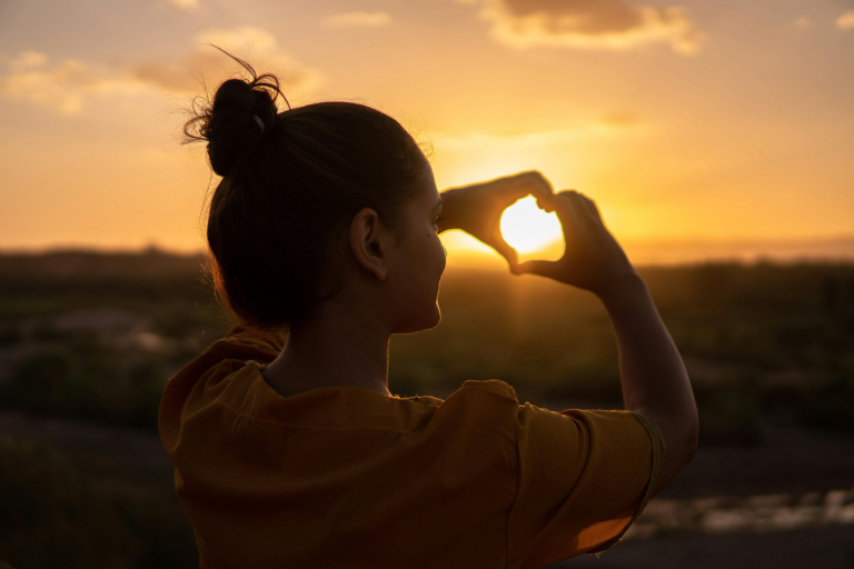Love Yourself First: a young man showing self love with a sunset background