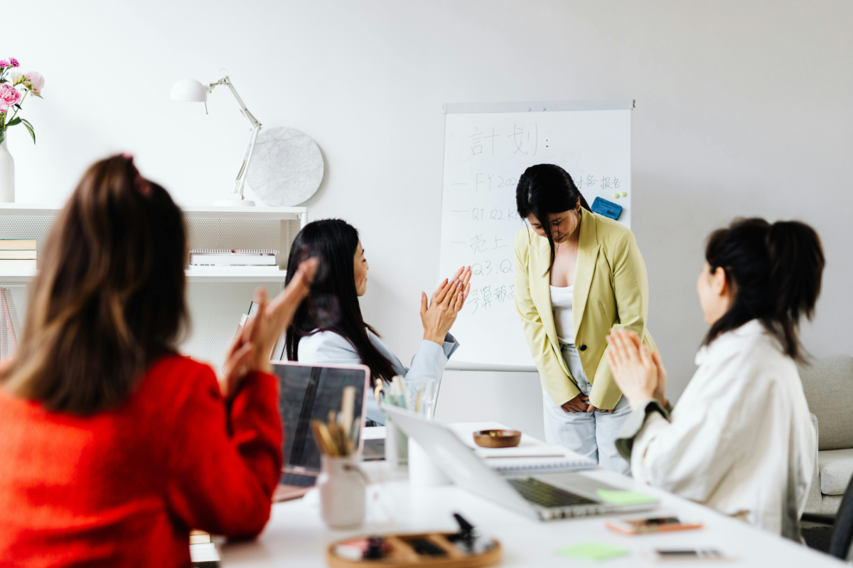Being Valued At Work: a young woman in yellow jacket being praised by her colleagues
